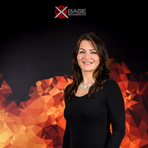 Brandschutz-Mitarbeiter-Portrait-x-base-1 Mitarbeiterin-Brandschutzfirma-steht-vor-Flammendesign-Plakat-Portraitbild